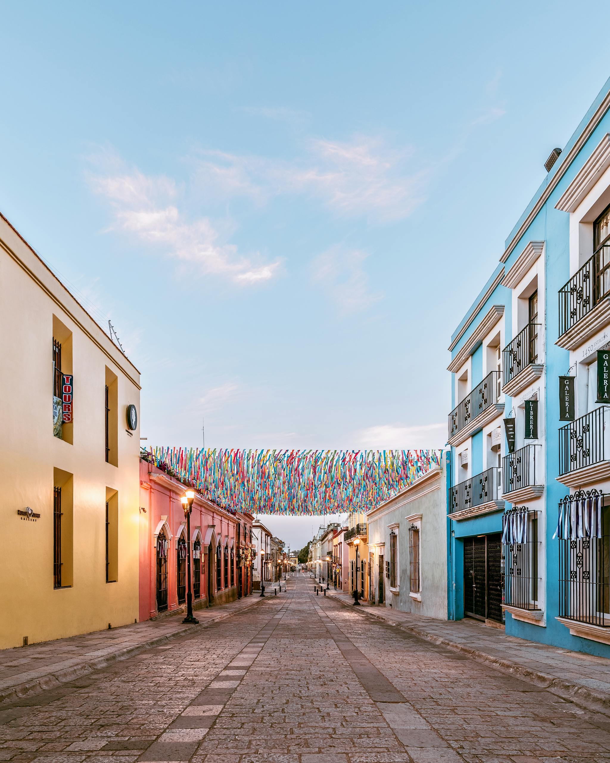 Charming street in Oaxaca with colorful facades and hanging decorations, perfect for travel inspiration.